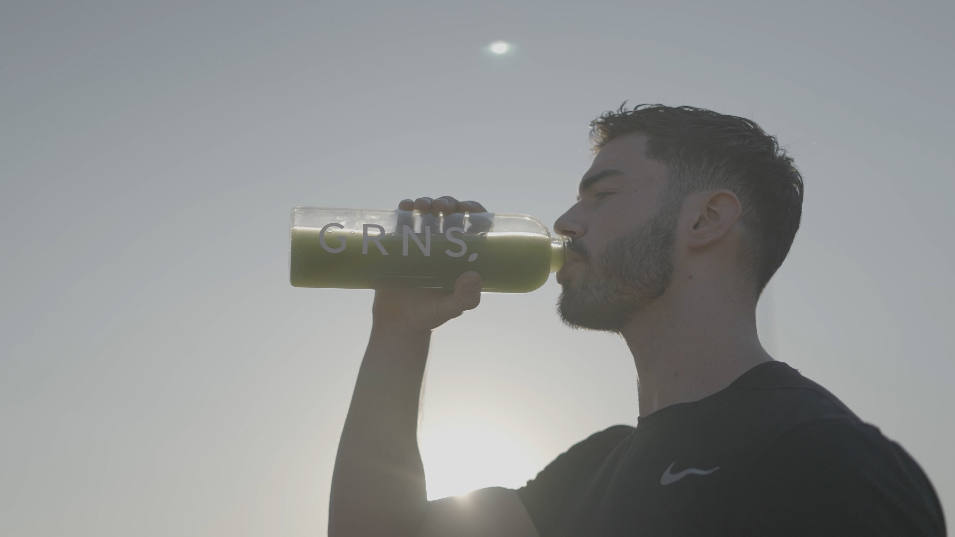 An atheltic man drinking greens powder in the sun