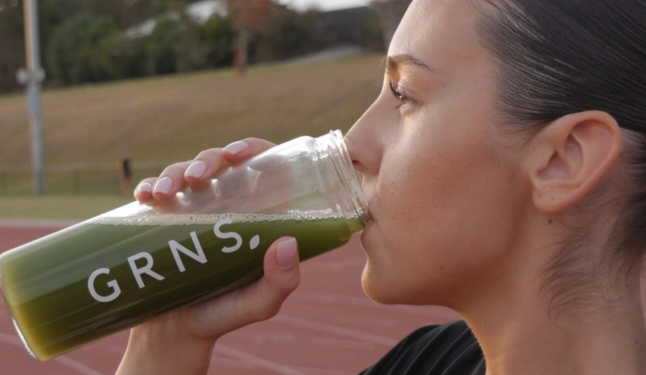 Girl drinking GRNS out of a GRNS drink bottle