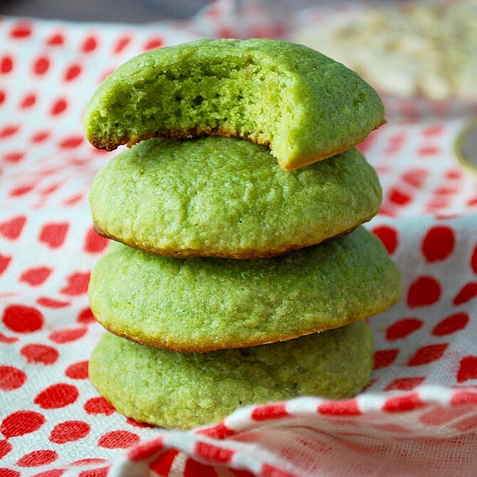 Stack of vibrant green cookies infused with GRNS greens powder, sitting on a cheerful red and white patterned cloth, showcasing a healthy twist on sweet treats
