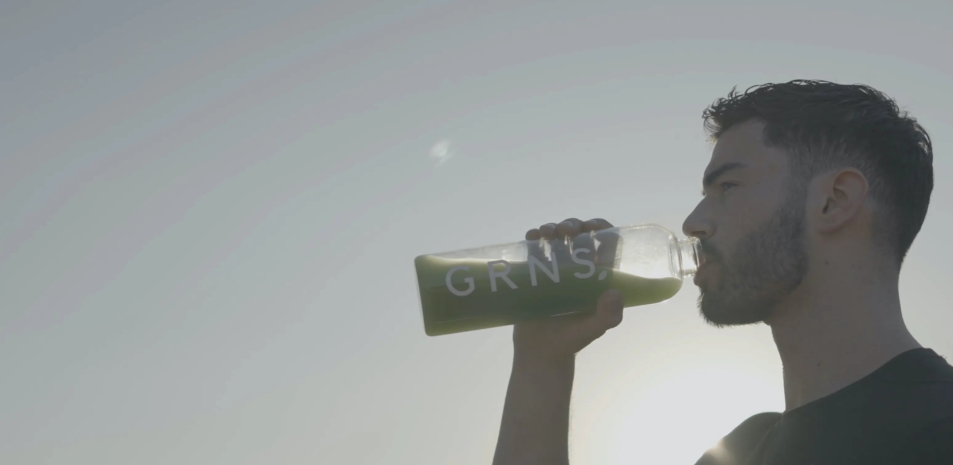 An atheltic man holding a glass of greens powder