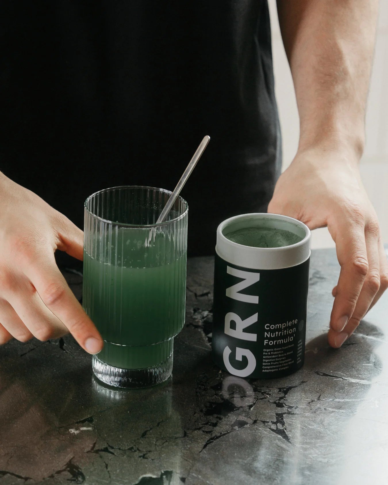 A girl holding a glass of greens pwoder
